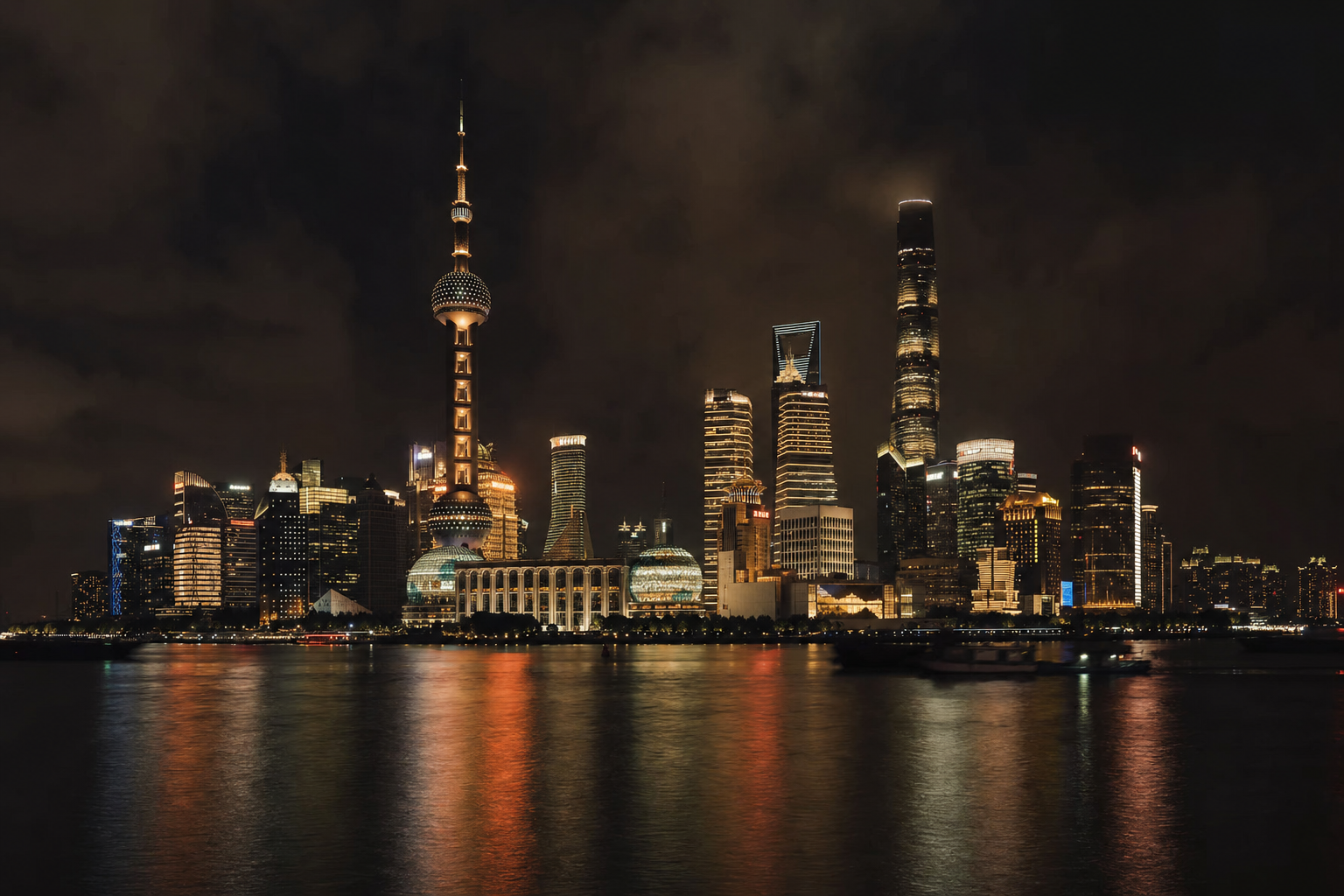 Shanghai skyline glowing across the river at night
